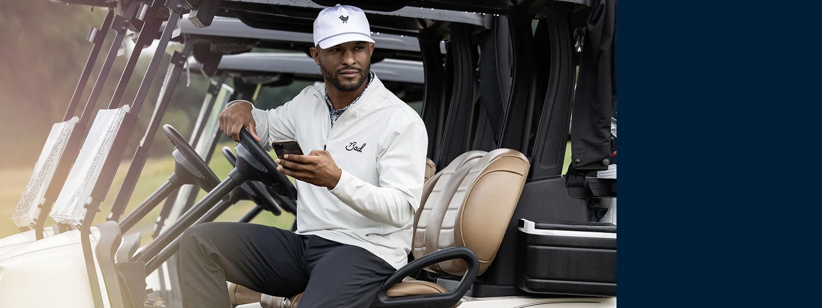 A man on his phone at a golf course.