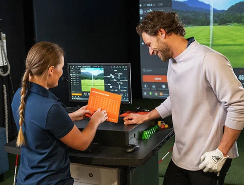 A golfer and a store associate looking at data.