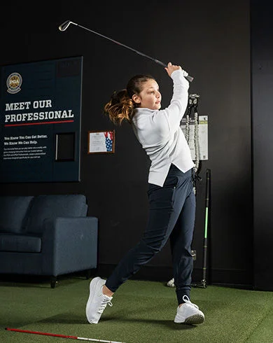 Young golfer practicing their swing indoors.