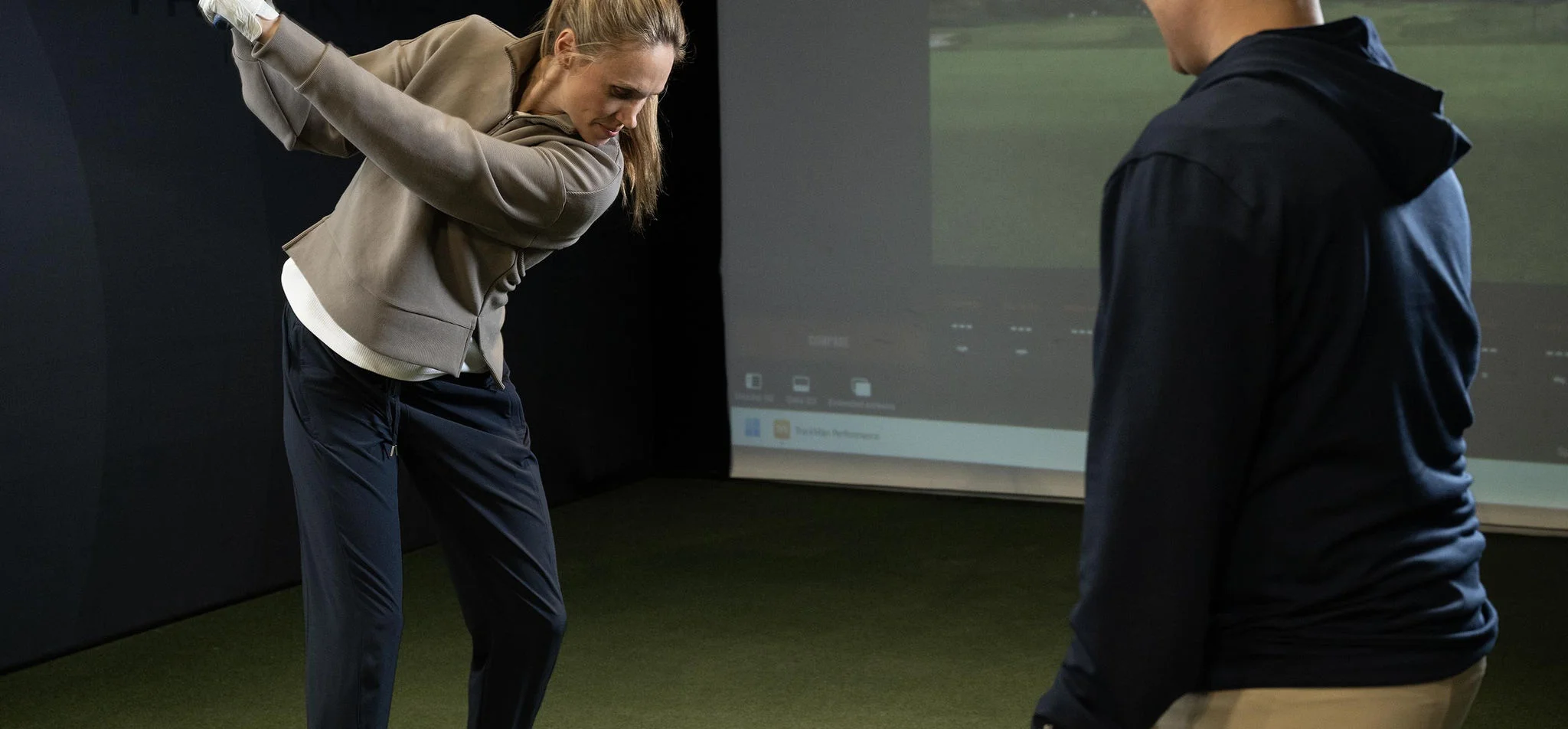 A woman swinging a club in the hitting bay.