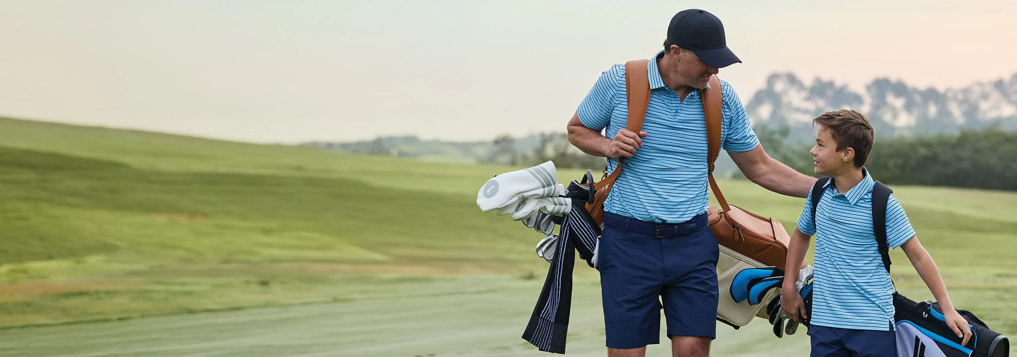A father and son walking down a fairway.