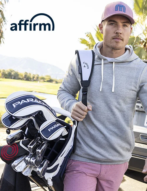 A man carrying his clubs from his car.