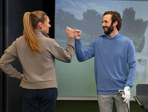 Two golfers fist-bumping.