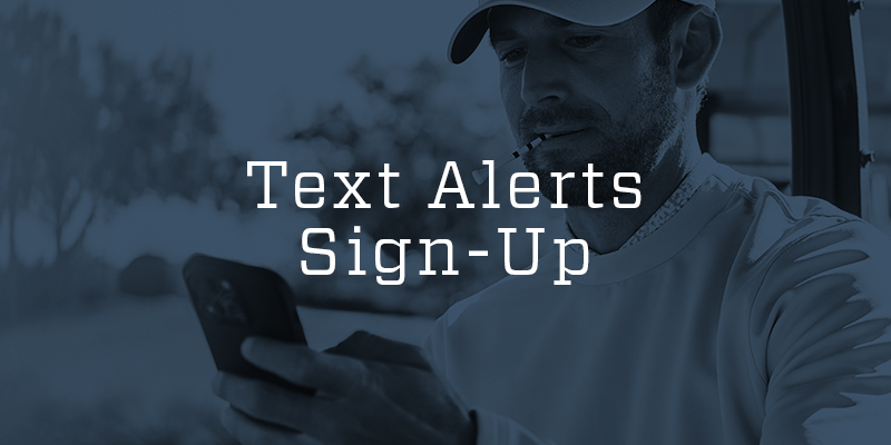 A man in a golf cart looking at his phone.